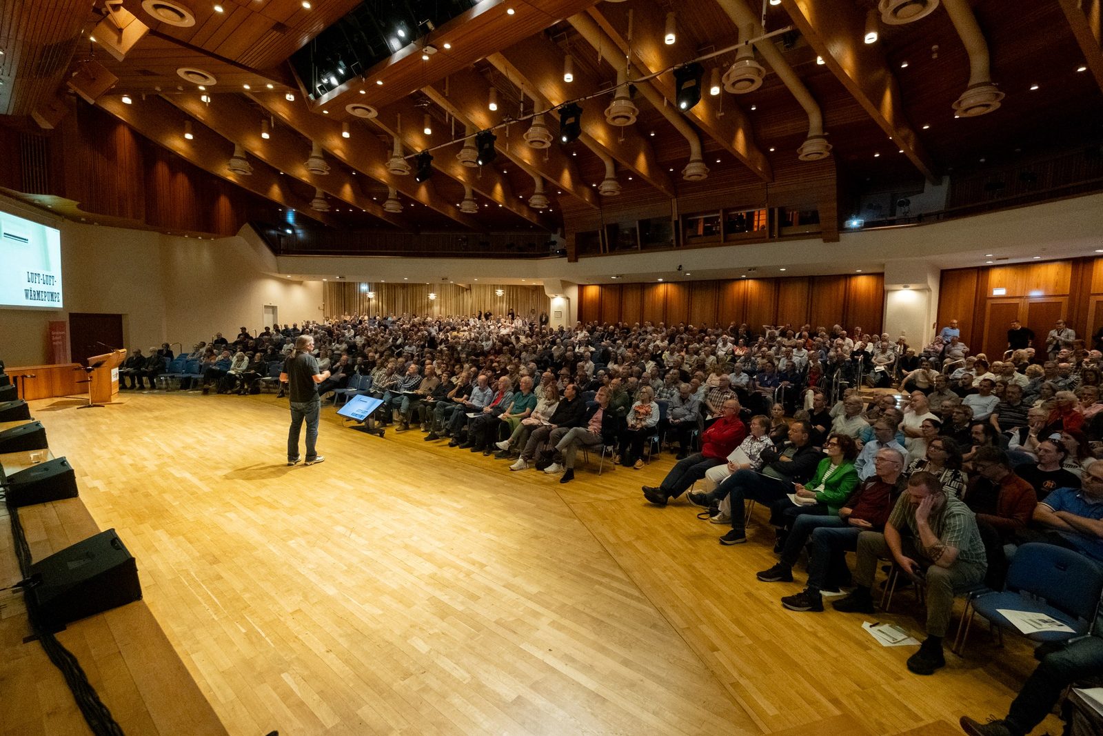 Blick von der Bühnenseite in den vollen Saal, Carsten Herbert spricht