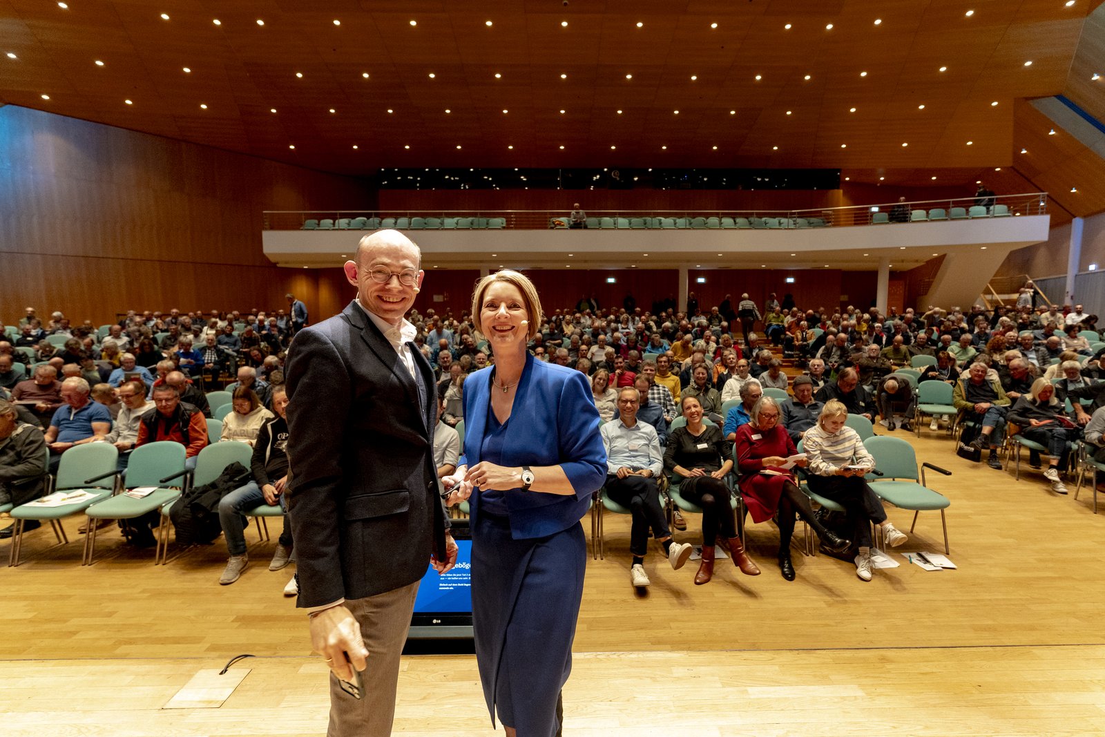 Dr. Marek Miara und Anja Floetenmeyer-Woltmann vor dem vollen Saal